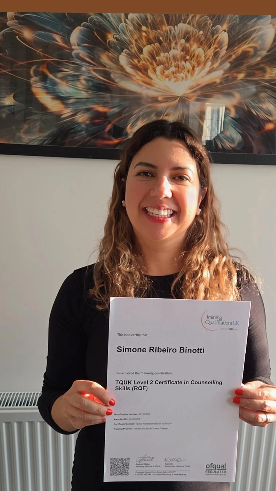 Professora Simone Binotti segurando seu certificado de qualificação no Reino Unido